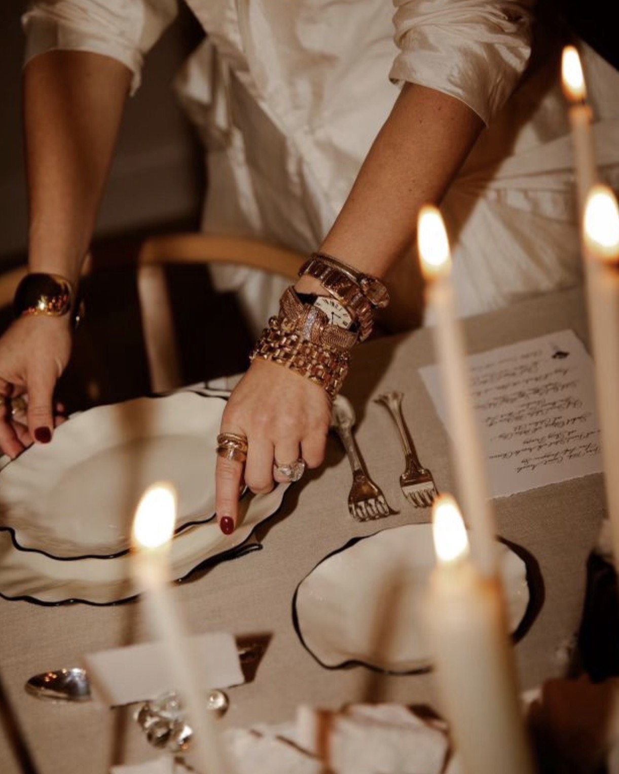 Candlelit table setting, hands placing a hand-painted plate