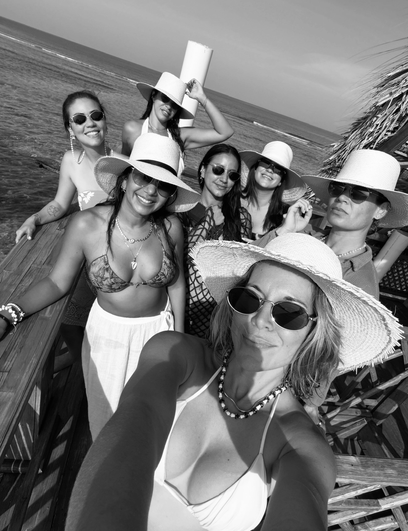 Women gathered on a wooden pier by the sea in black and white